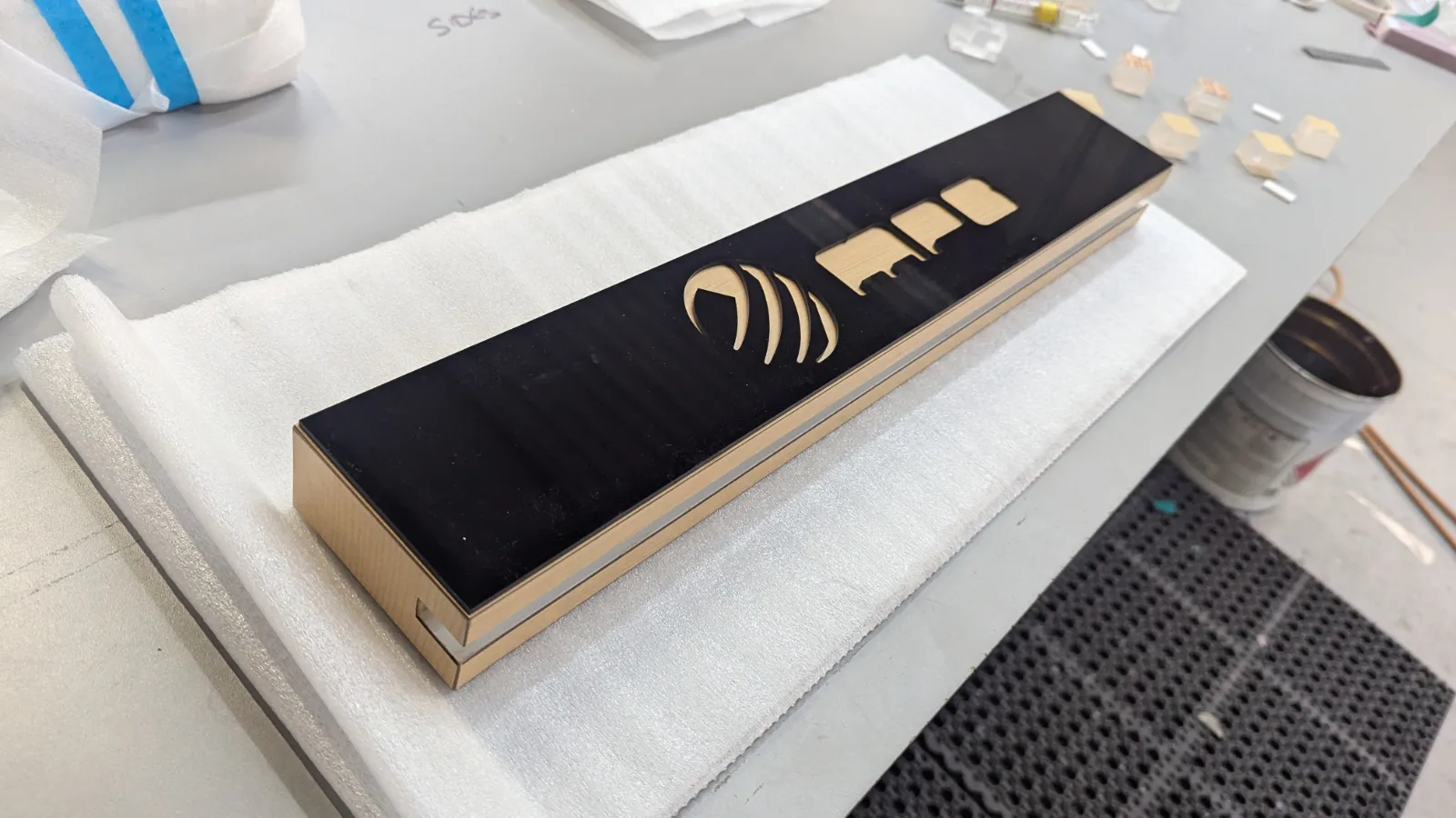 Black acrylic and maple header with CNC-cut logo on the finishing bench at DNS