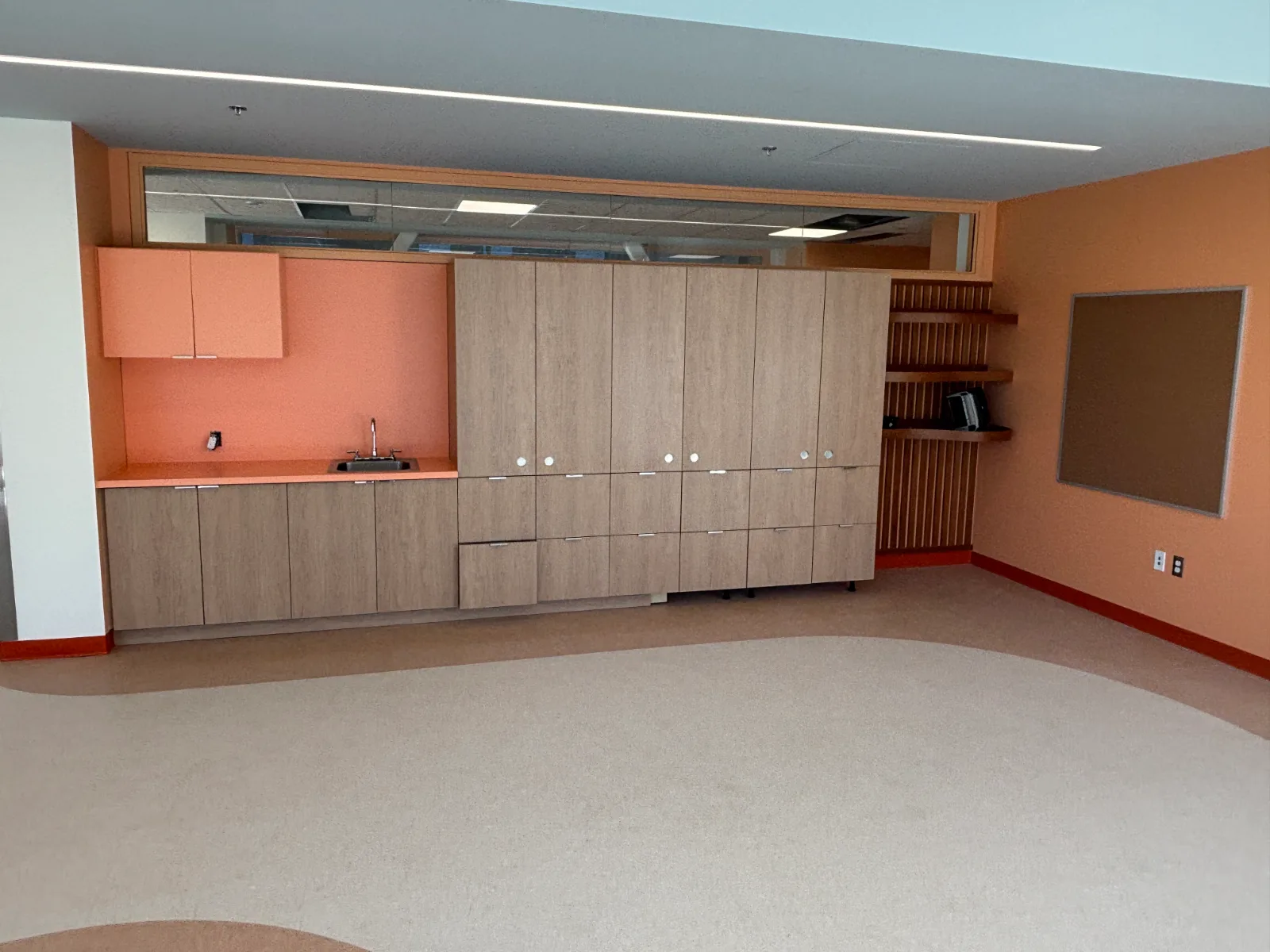 Classroom casework wall with woodgrain tall storage, sink run and slatted cubby shelving at Brownsburg school