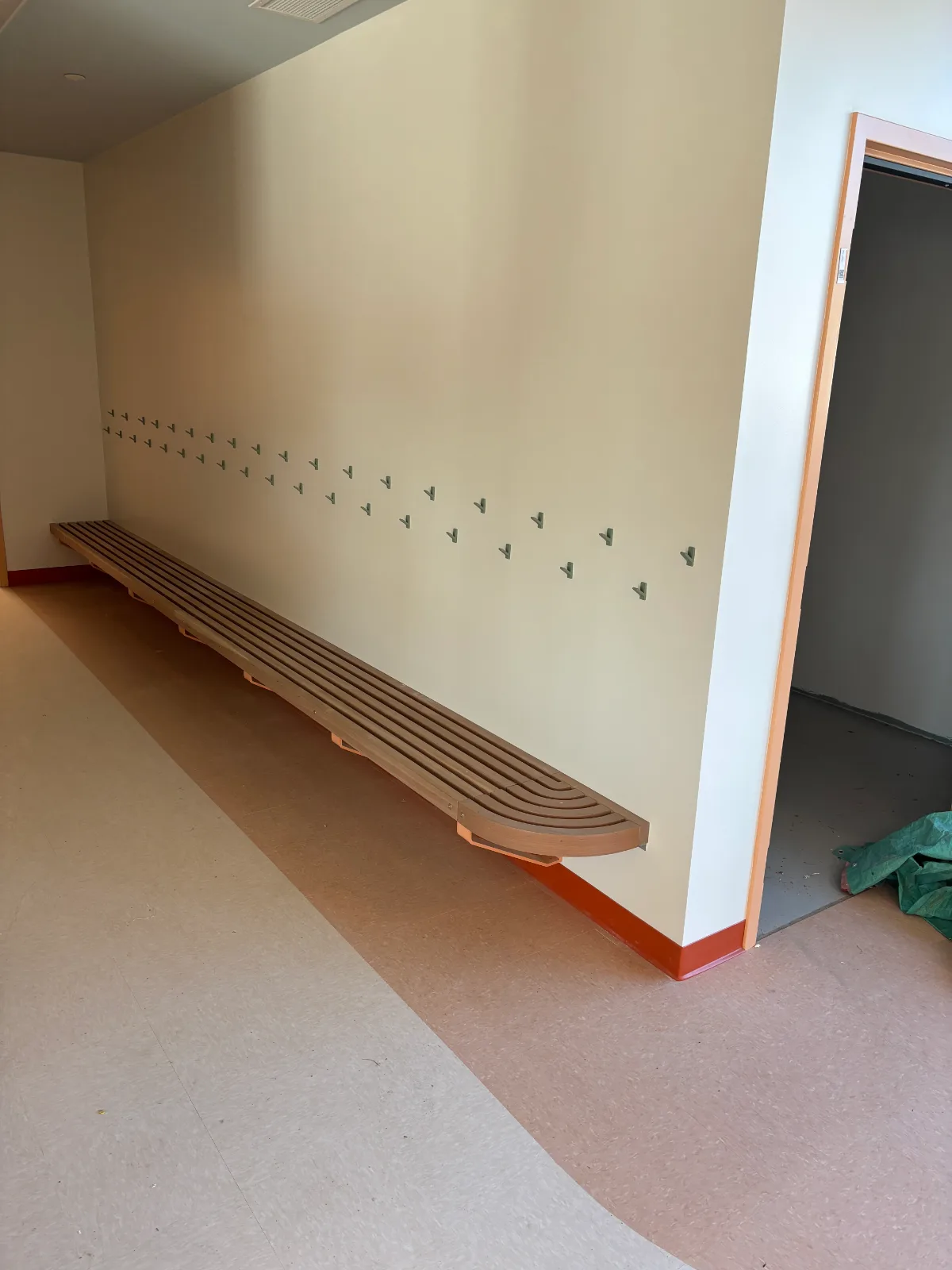 Wall-hung slatted wood bench with curved end in a school corridor at Brownsburg