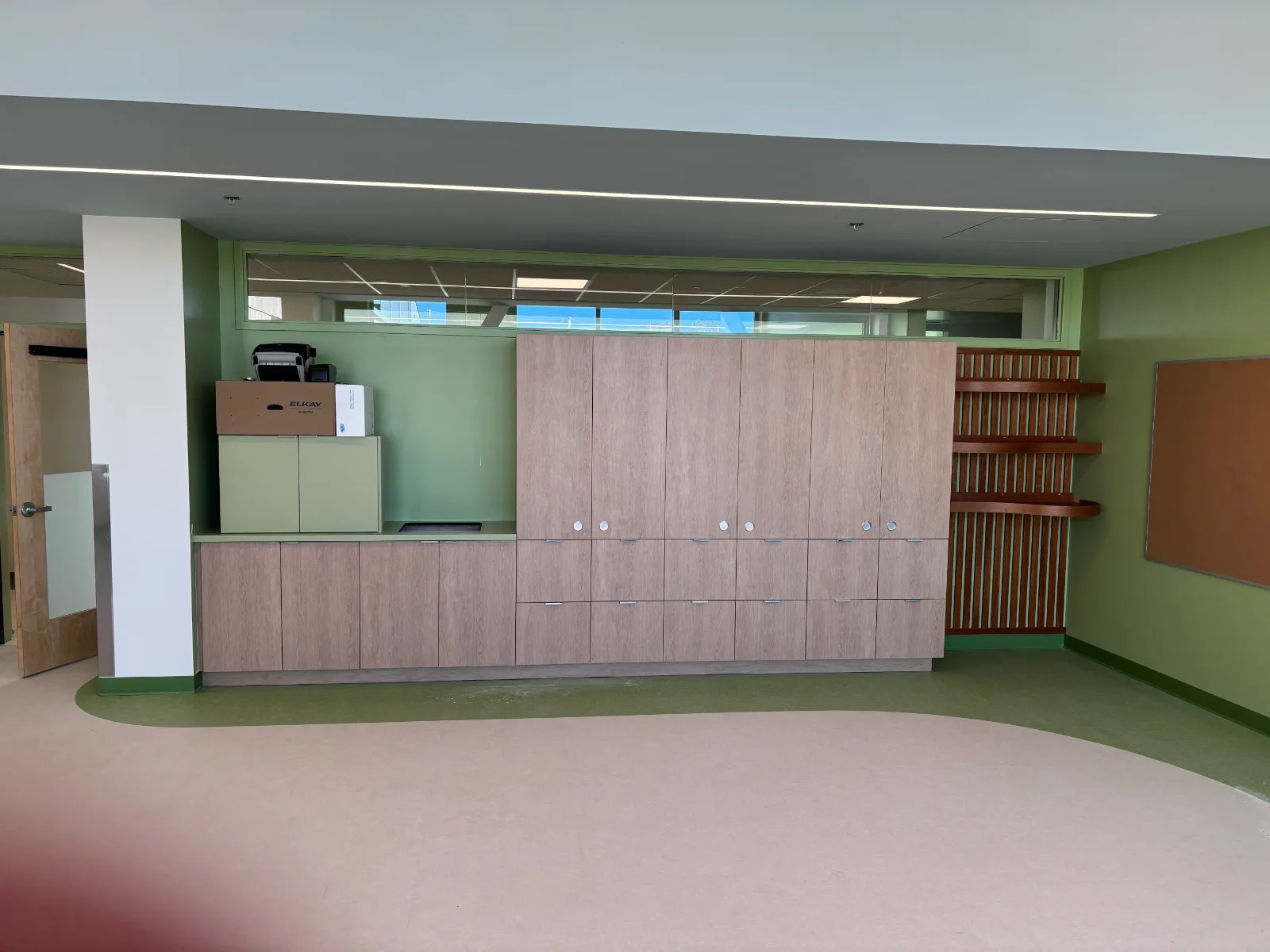 Full-height woodgrain classroom storage with laminate counter and curved display shelves at Brownsburg school