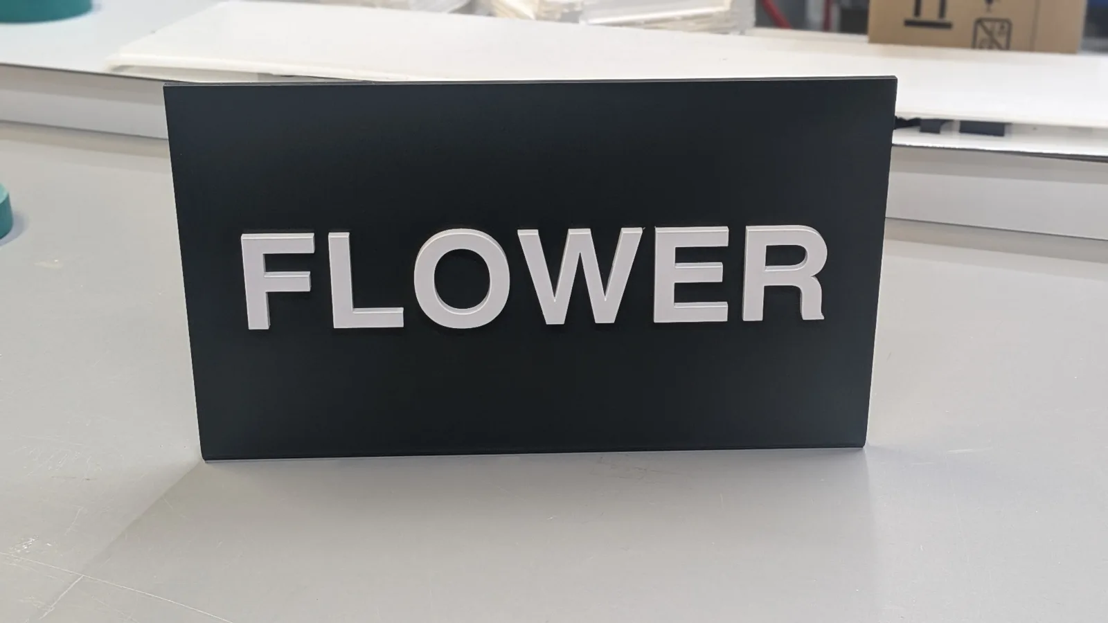 Matte black dispensary category sign with raised CNC-cut lettering