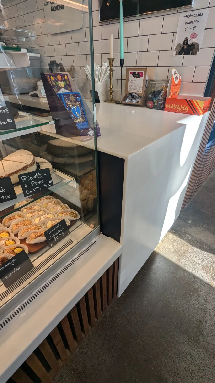 Mitred white solid-surface waterfall counter end beside a pastry case at Freebird Market