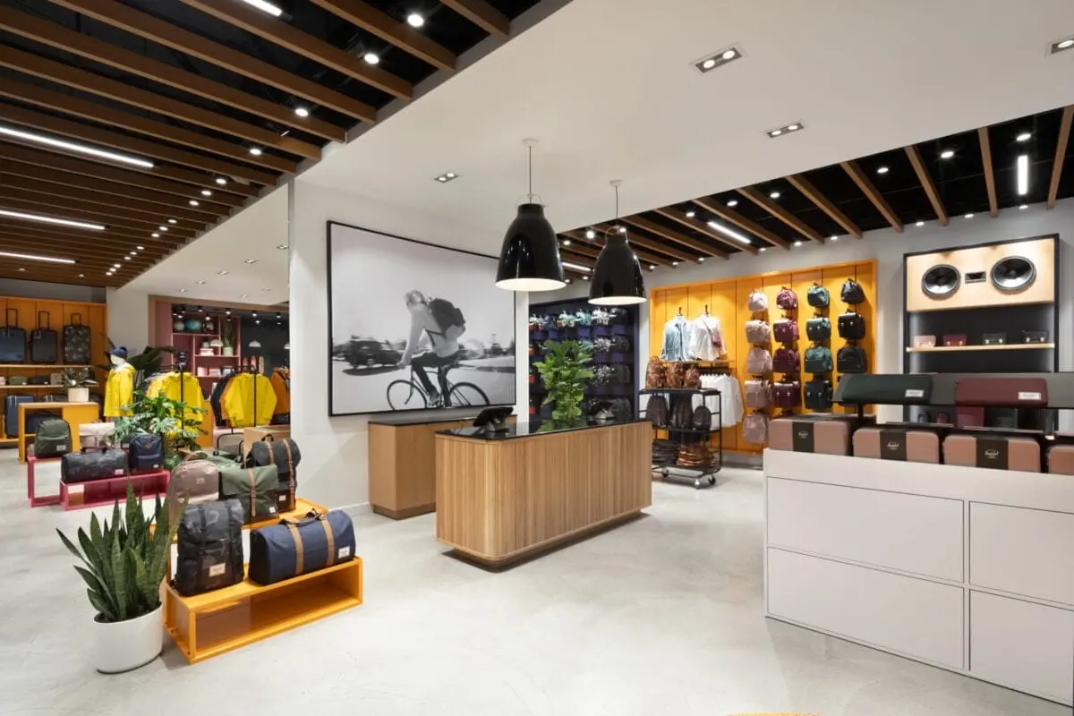 Herschel Supply Co. store interior with an oak slat ceiling, timber display island and wall-mounted bag merchandising.