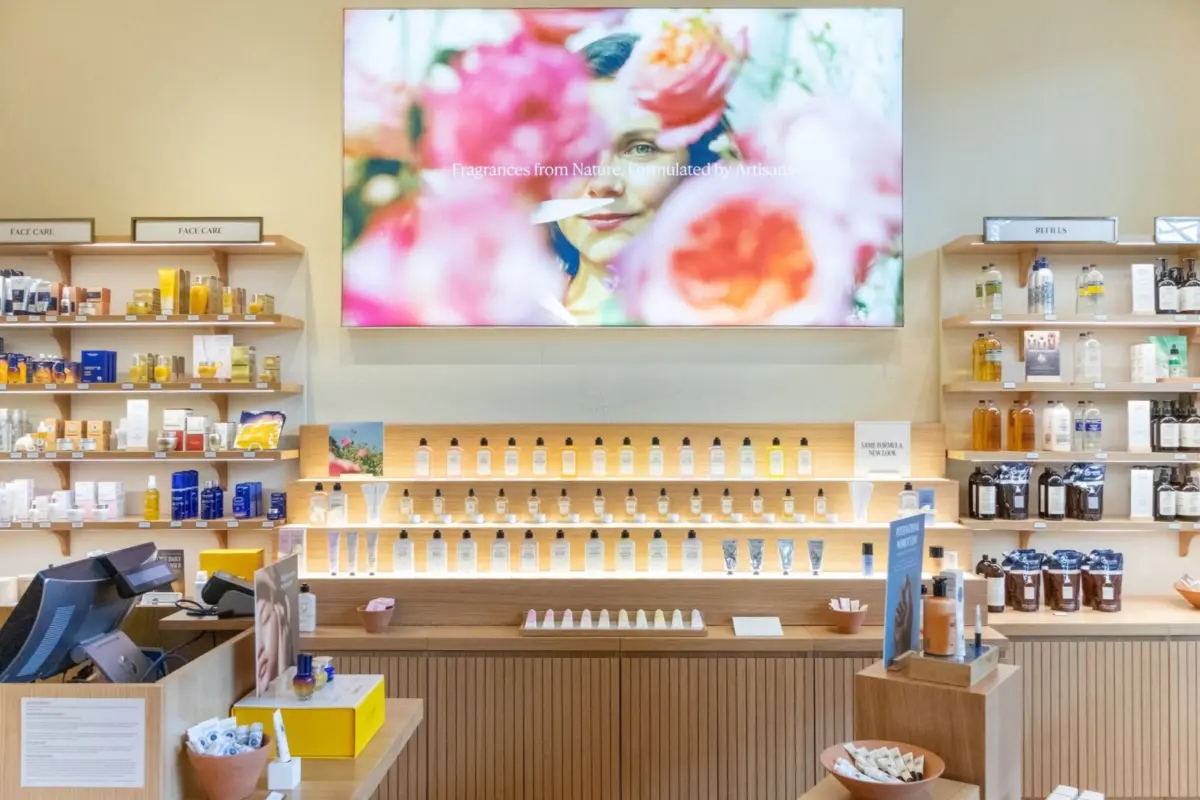 Long illuminated retail display run in oak with concealed LED lighting and integrated point-of-sale casework, manufactured by DNS Industries
