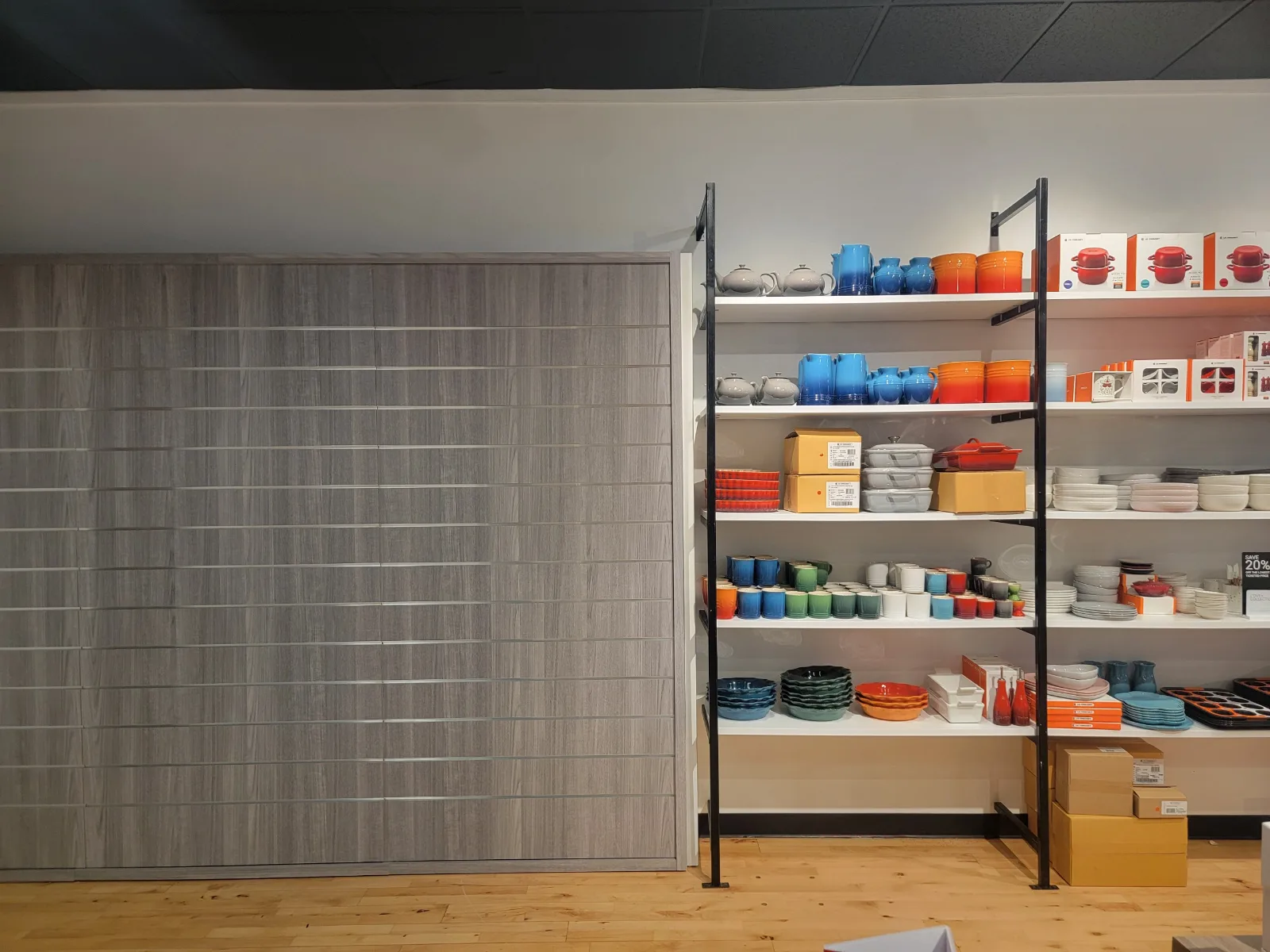 Wood-grain slatwall beside black metal-framed open shelving at Le Creuset Kittery, Maine