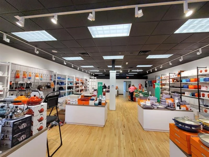 Finished store with white display tables and merchandised wall shelving at Le Creuset Kittery, Maine