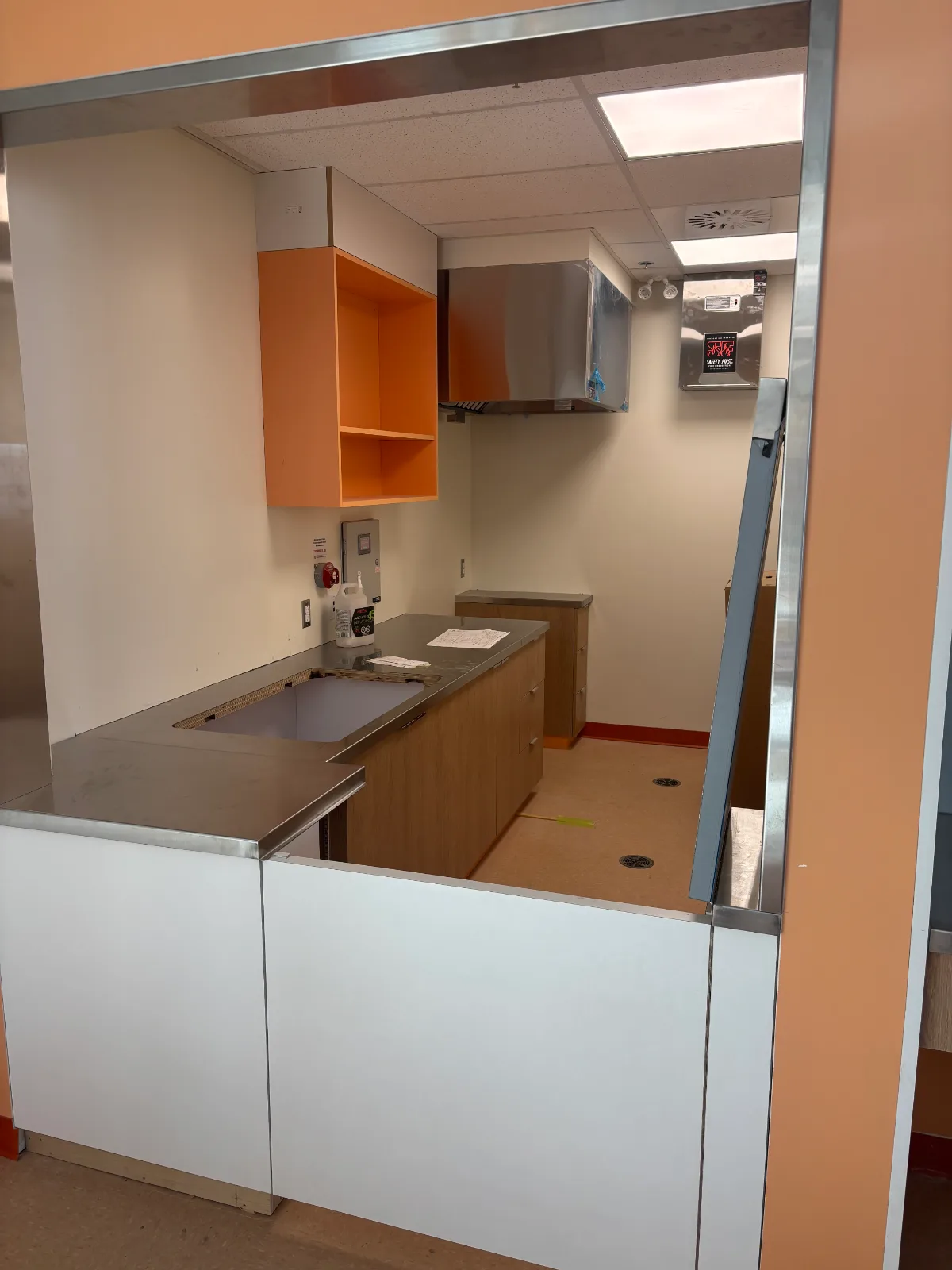 Kitchenette pass-through with stainless counter and woodgrain base cabinets at Brownsburg school