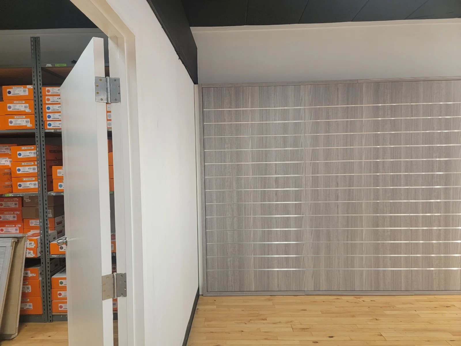 Full-height wood-grain laminate slatwall with aluminum inserts at Le Creuset Kittery
