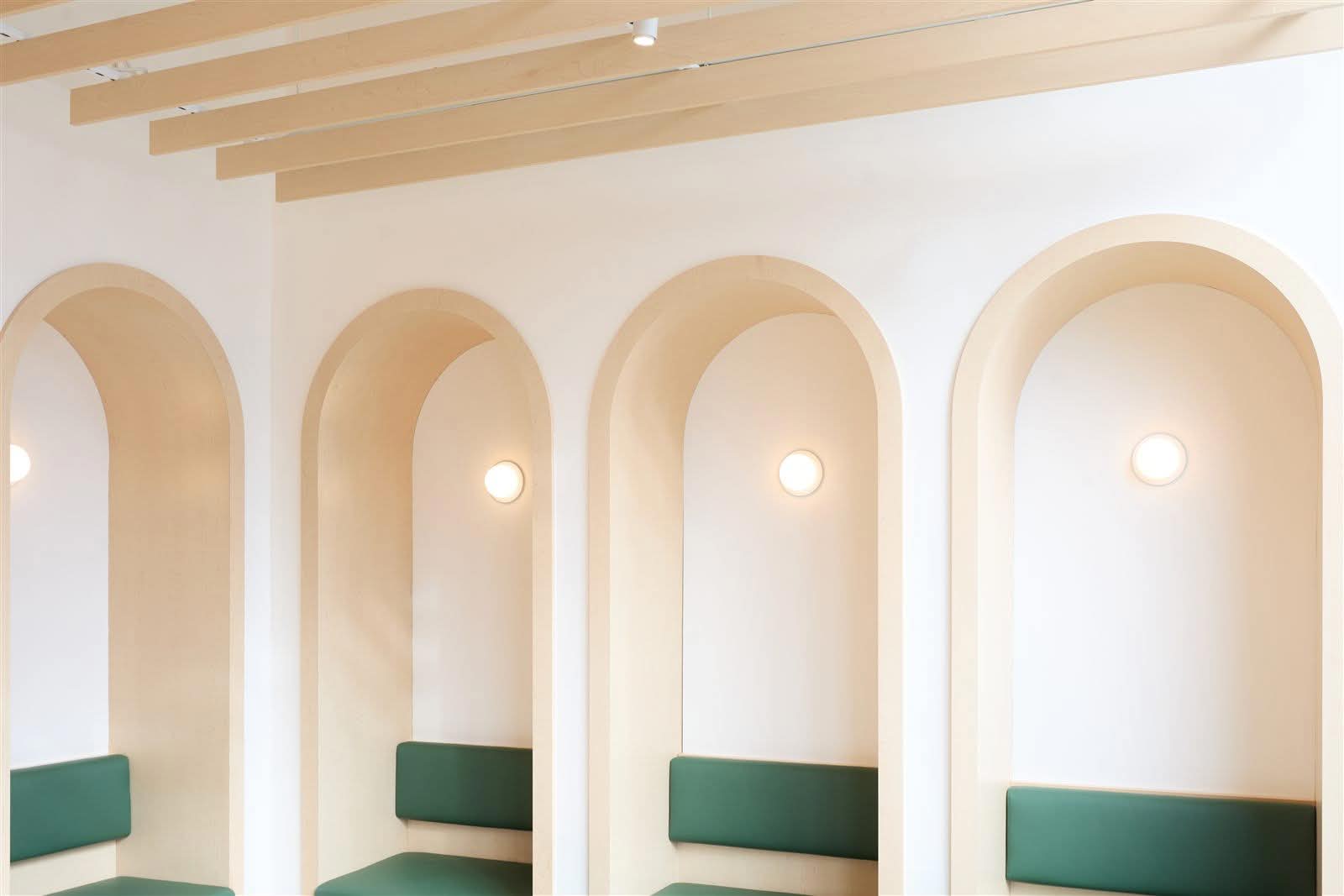 Four arched maple niches with green upholstered banquette seating in the Juno Veterinary waiting area