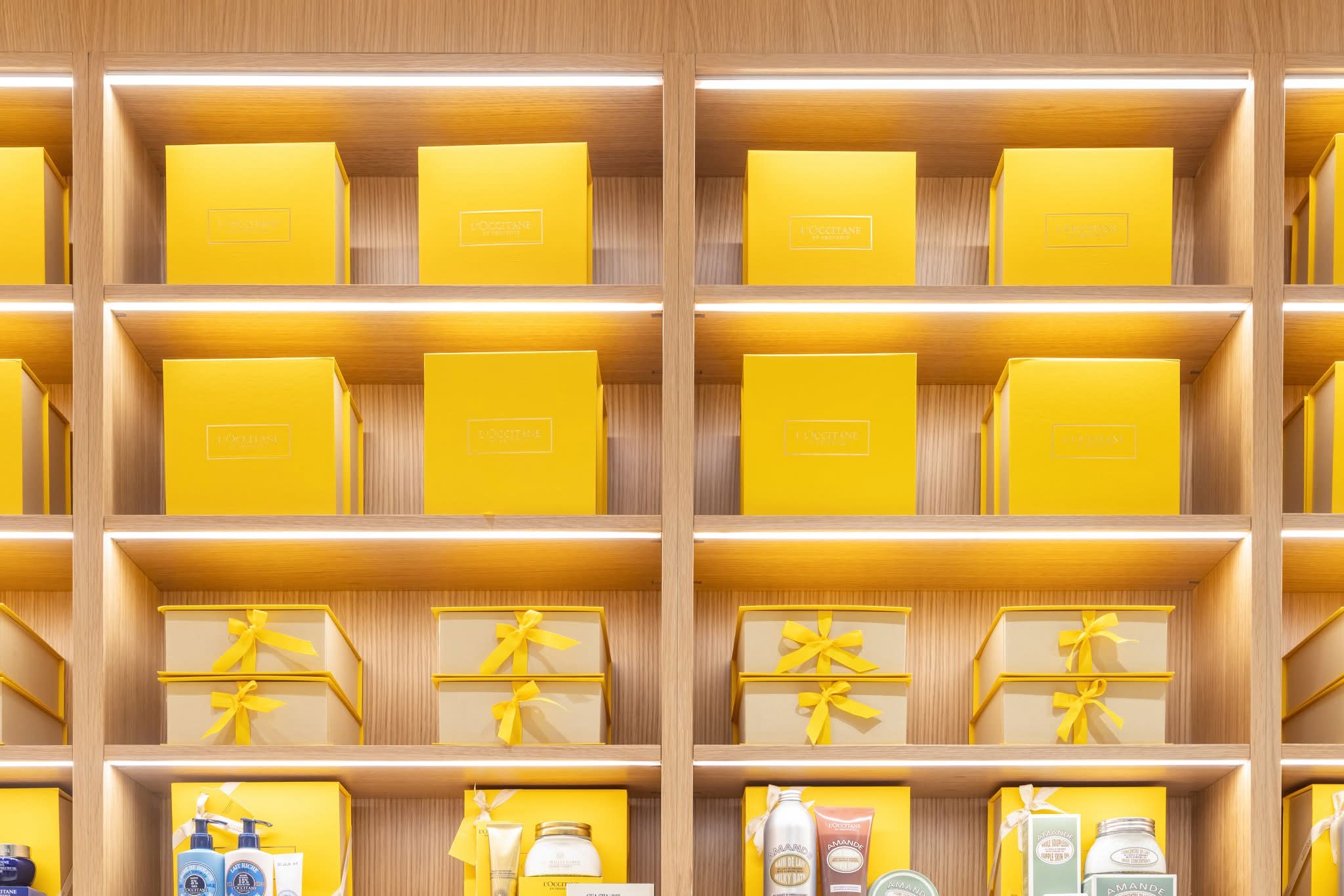 Illuminated oak shelving system with integrated LED strip lighting in each shelf, manufactured by DNS Industries for L’Occitane
