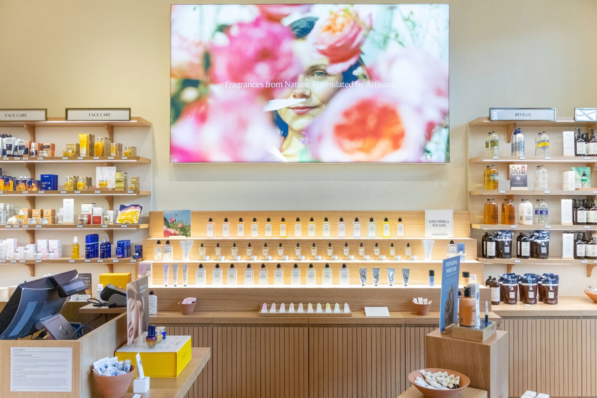 Long illuminated retail display run in oak with concealed LED lighting and integrated point-of-sale casework, manufactured by DNS Industries
