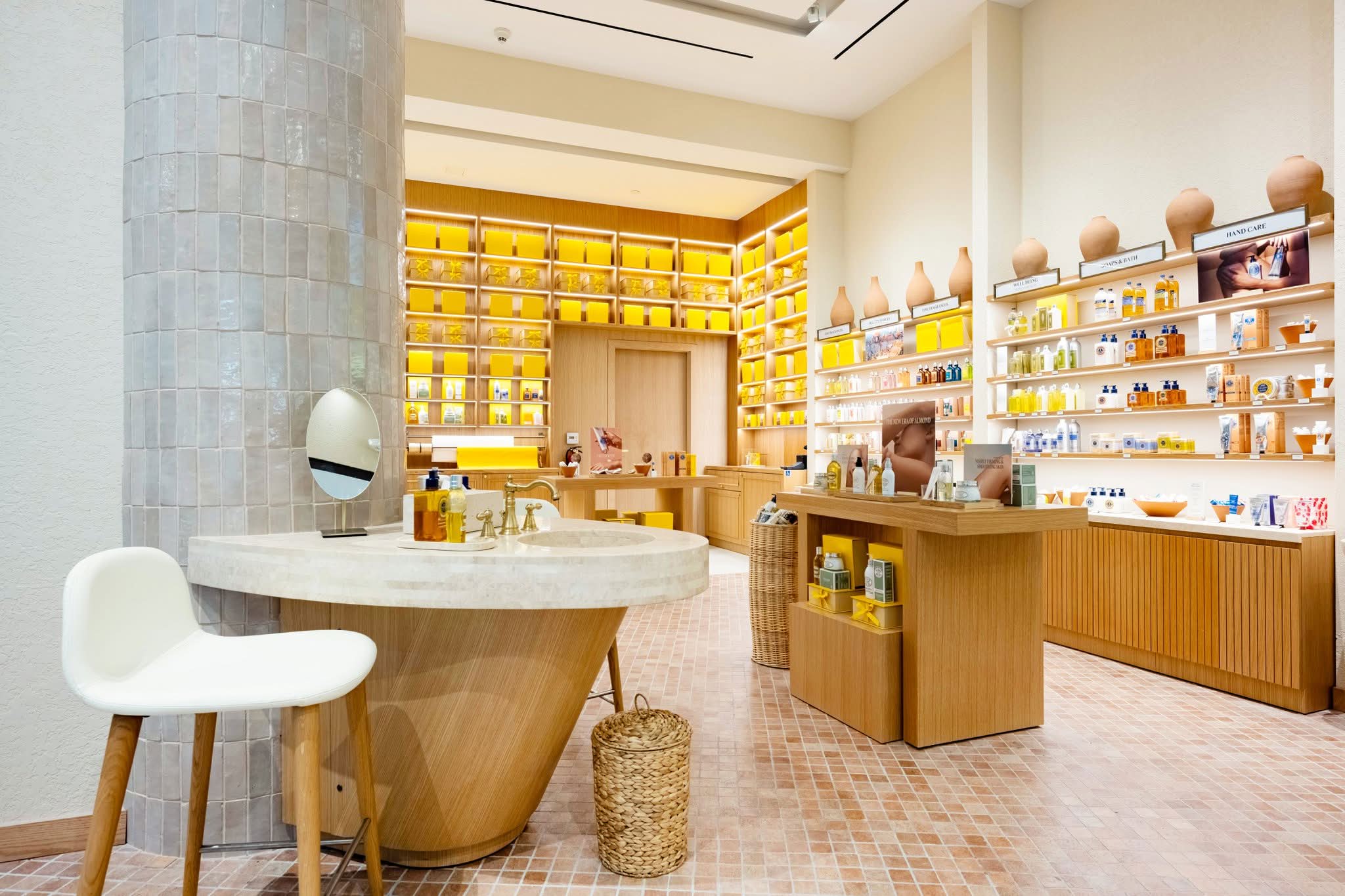 Travertine consultation table and backlit product wall in the L’Occitane Santa Anita store, fabricated by DNS Industries