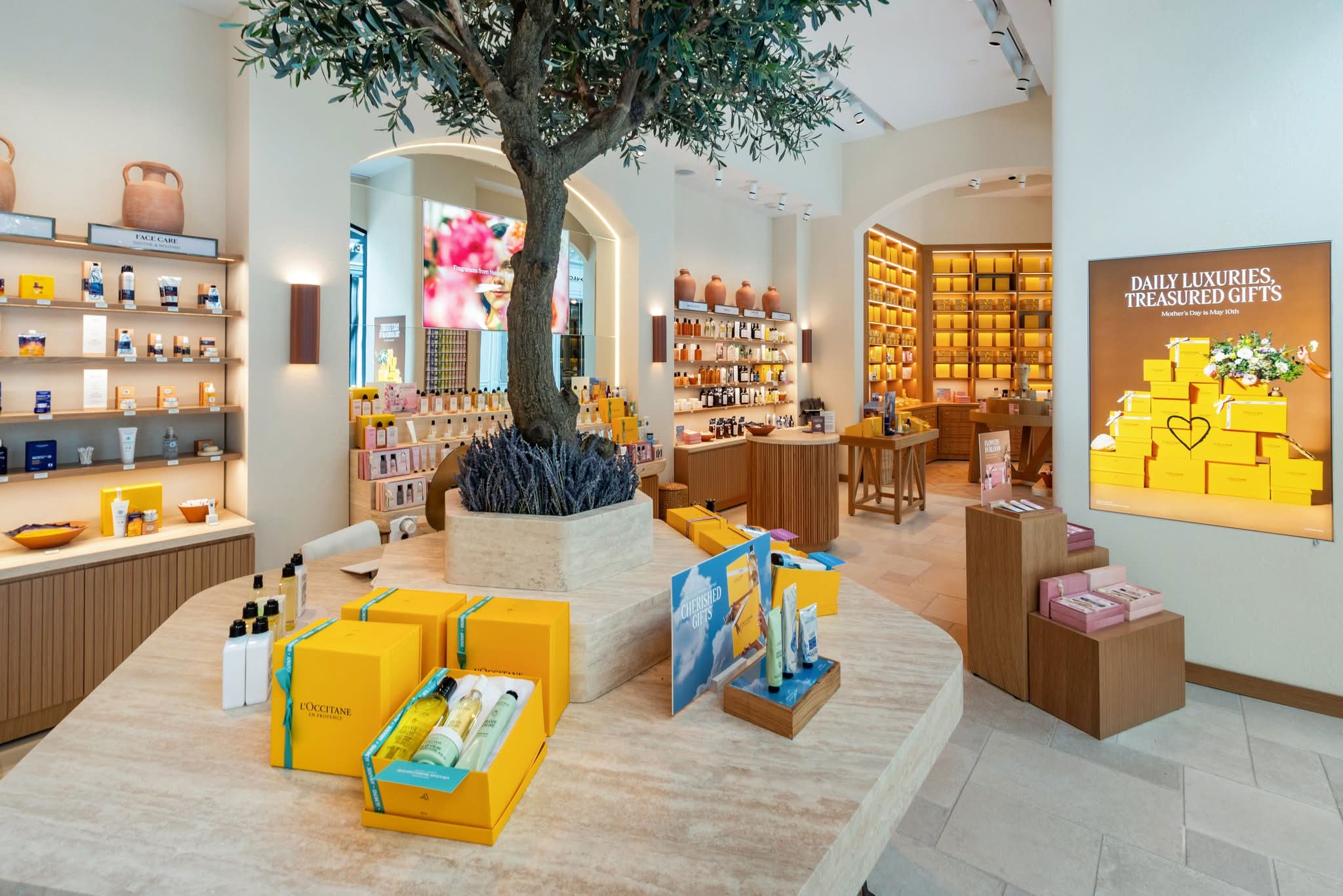 Travertine plinth, arched illuminated display niches and fluted oak casework in an L’Occitane store at Sherway Gardens, Etobicoke, manufactured by DNS Industries