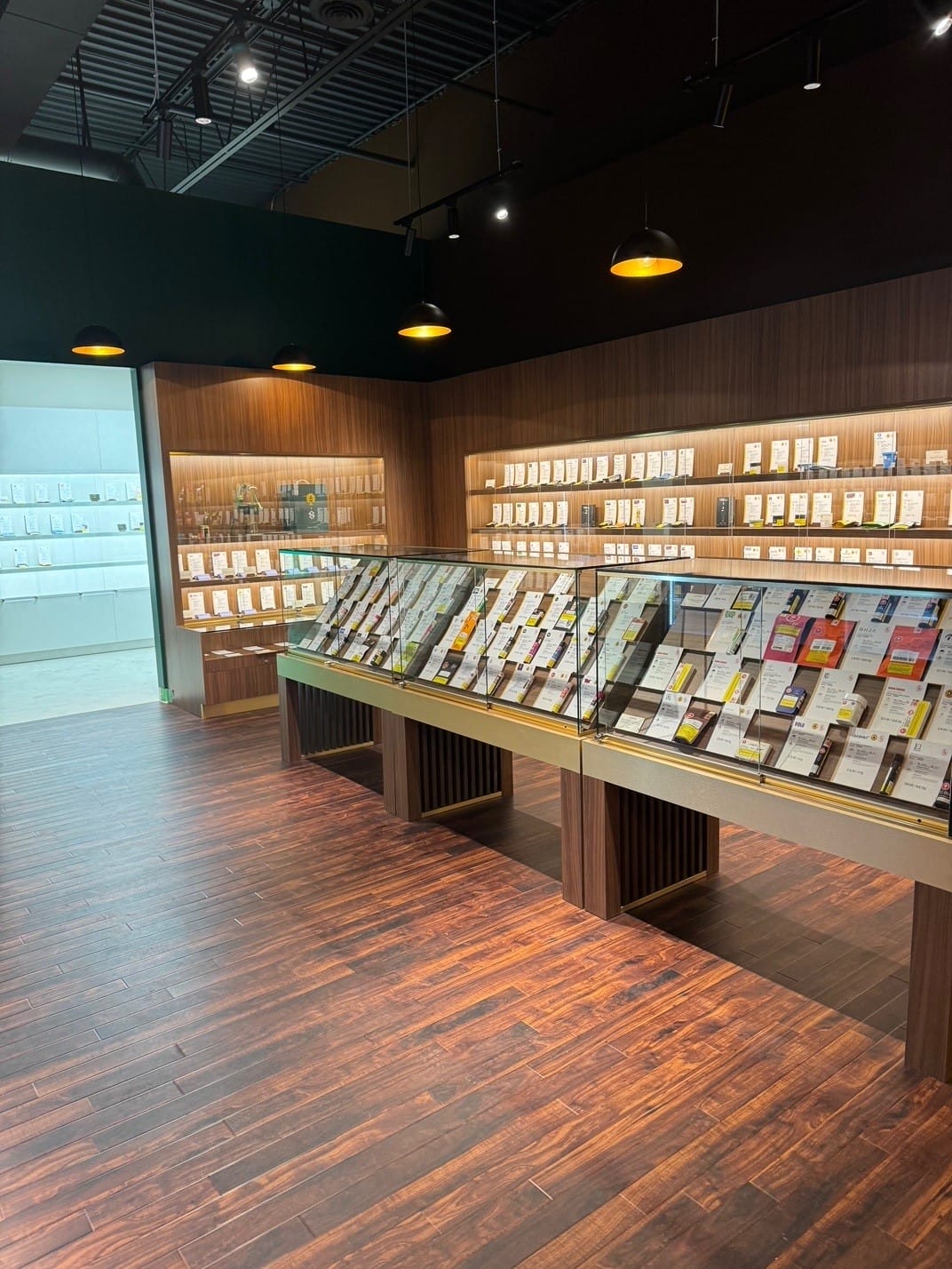 Long wood display tables with product under glass domes on the Woods Cannabis sales floor