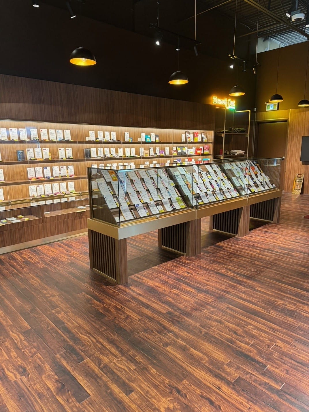 Row of wood display tables with product stands and glass domes in Woods Cannabis