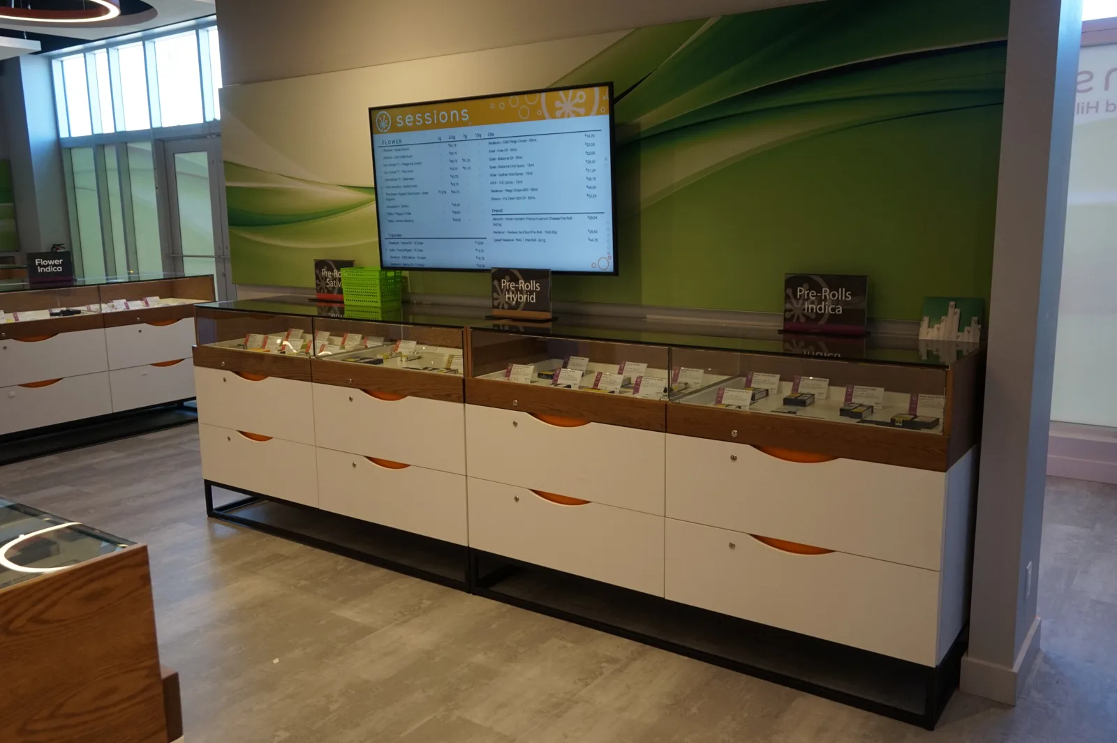 Wall showcase at Sessions Cannabis Stoney Creek with glass cases over white lockable drawers