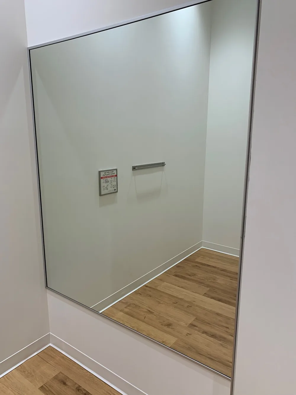 Uniqlo fitting room with a full-height framed mirror and white walls